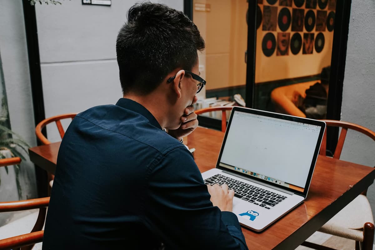 A man thinking in front of a laptop, thinking.